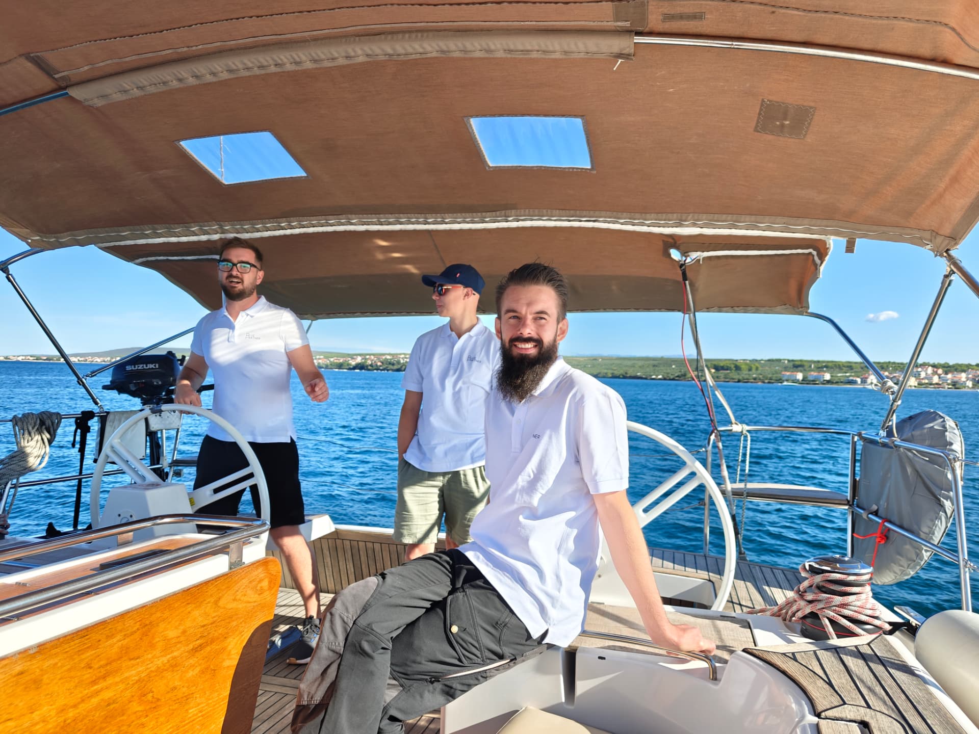 Tre kollegor i Blue Partner-piké ombord på segelbåten